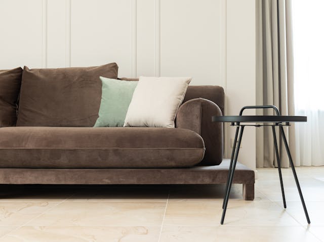 brown couch with cream and green throw pillows next to a black coffee table