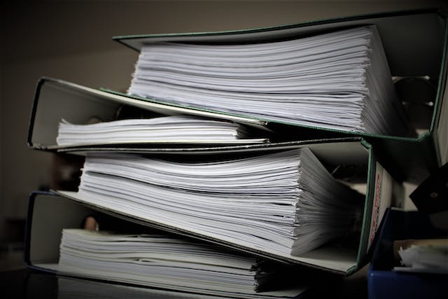 A stack of several large binders full of paper.