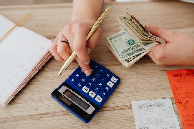 A person counting money with a calculator.